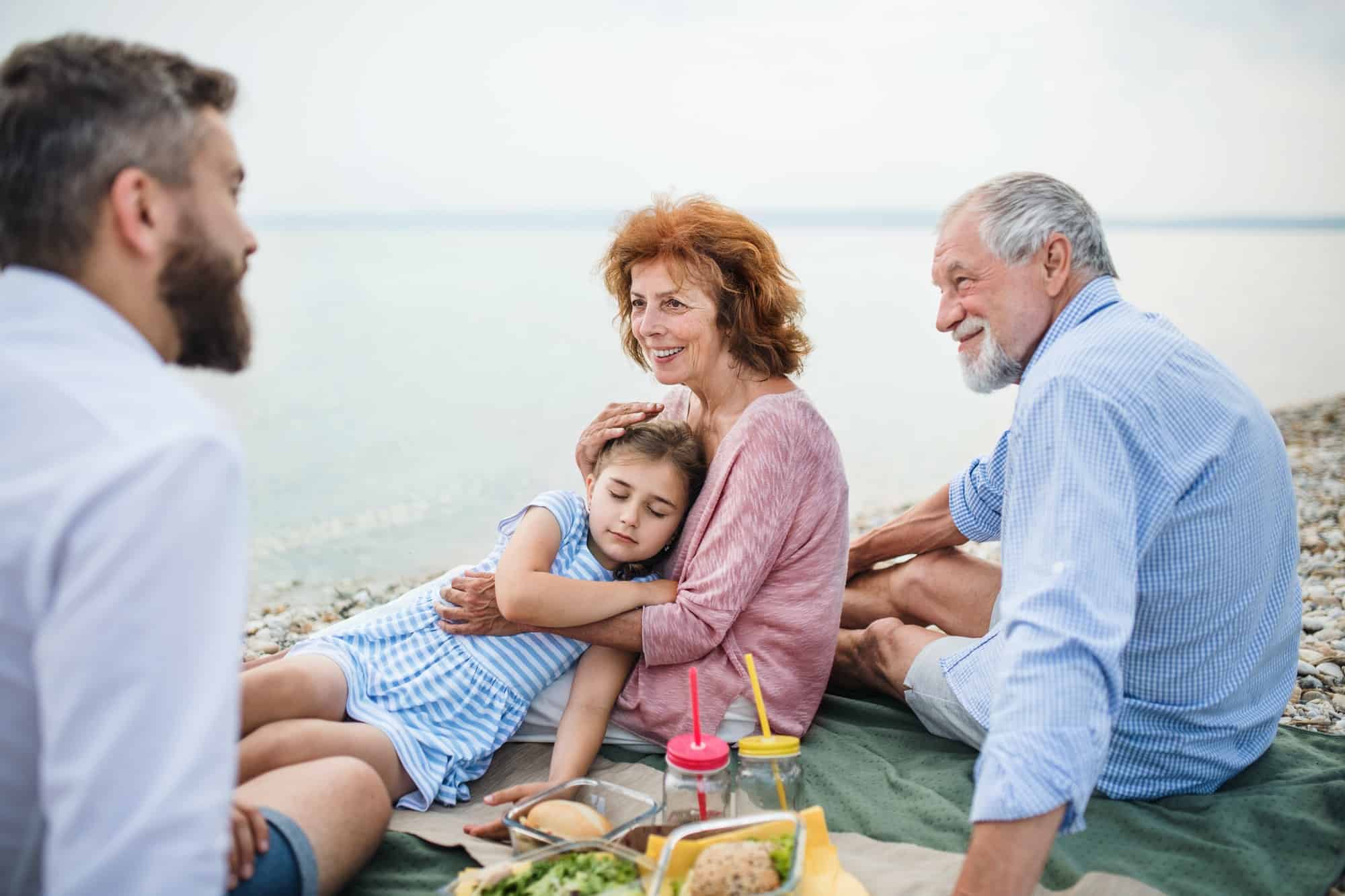 Multigeneration family on a holiday by the lake, having picnic