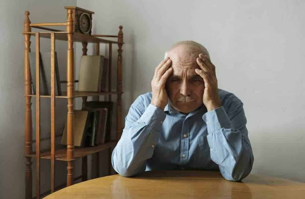 Worried elderly man with his head in his hands